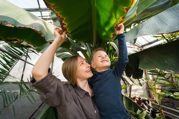 Moeder en zoon kijken naar grote bladeren van bananenboom