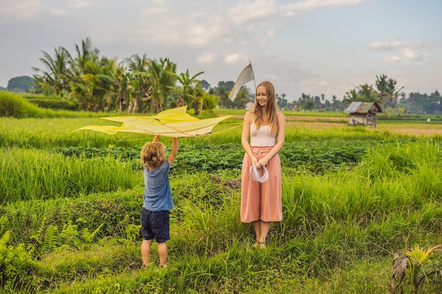 Moeder en zoon lanceren een vlieger in een rijstveld op Ubud Bali, Indonesië