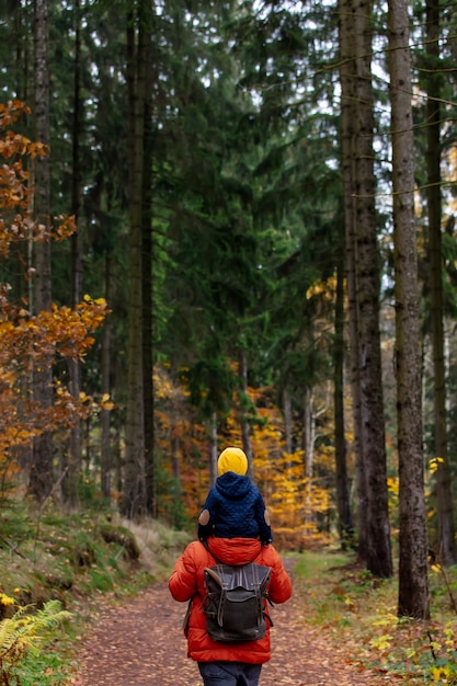 Moeder en zoon lopen in de herfst door het bos