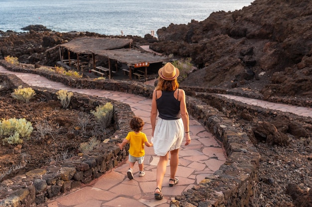 Foto moeder en zoon lopen op een pad naar het strand bij zonsondergang op het strand van tacoron op de canarische eilanden el hierro