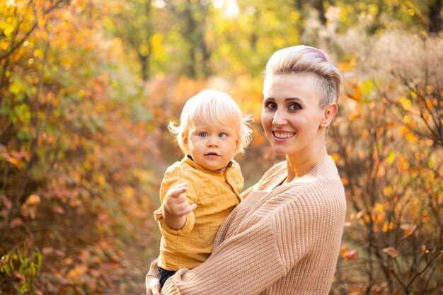 Moeder en zoon op herfstachtergrond met gouden bomen