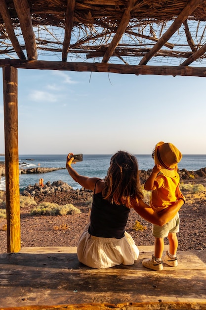 Moeder en zoon op vakantie nemen een foto op het strand van Tacoron in El Hierro Canarische Eilanden jongen met hoed