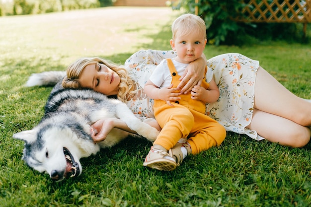 Moeder en zoon poseren met een hond op het gras