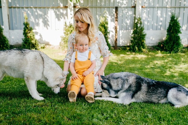 Foto moeder en zoon poseren met twee honden in de tuin