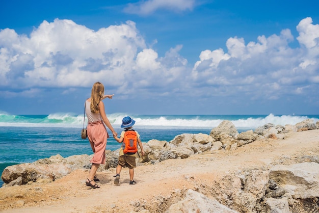 Moeder en zoon reizigers op verbazingwekkende Melasti Beach met turquoise water, Bali Island Indonesië. Reizen met kinderen concept
