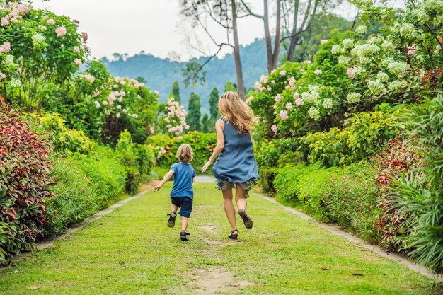 Moeder en zoon rennen rond in het bloeiende tuinconcept voor een gelukkige gezinslevensstijl