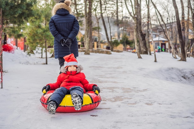 Moeder en zoon rijden op een opblaasbare winter slee buis Winter plezier voor de hele familie