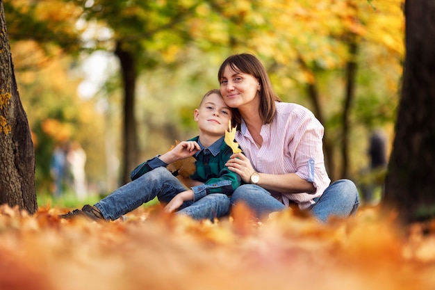 Moeder en zoon rusten in een prachtig kleurrijk herfstpark