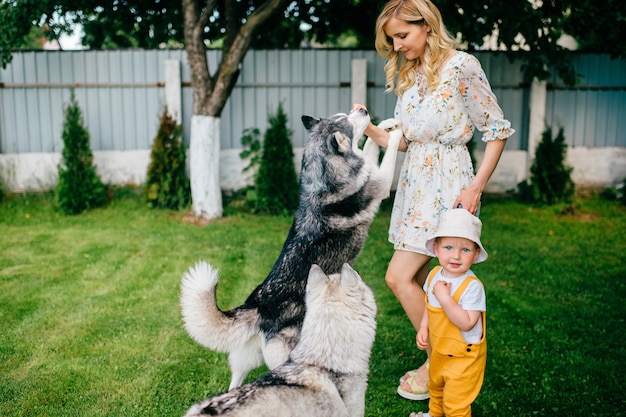 Moeder en zoon spelen met twee honden in de tuin