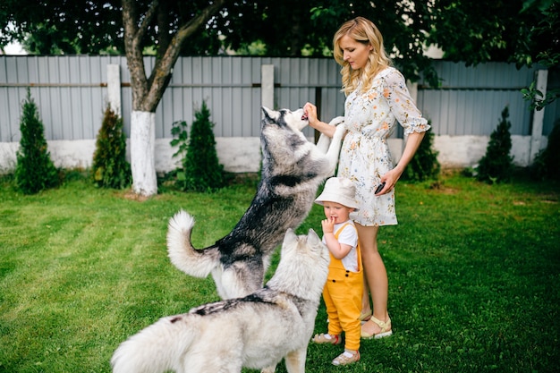 Moeder en zoon spelen met twee honden in de tuin