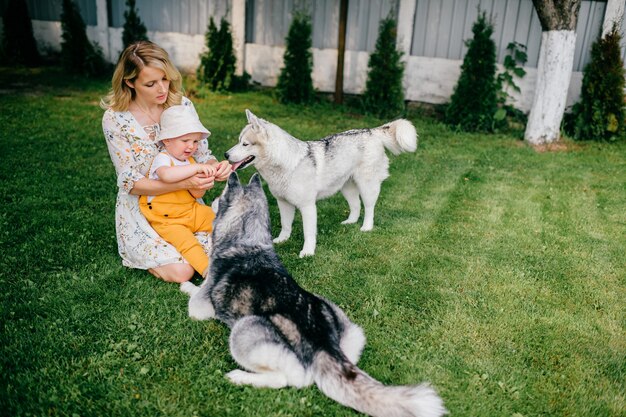 Moeder en zoon spelen met twee honden in de tuin