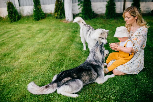 Foto moeder en zoon spelen met twee honden in de tuin