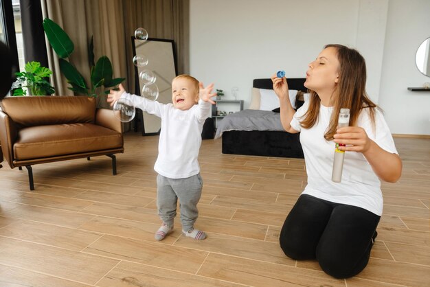 Moeder en zoon spelen met zeepbellen het kind geniet van de zeepbellenfamilie die thuis zit pl