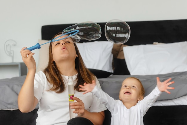 Moeder en zoon spelen met zeepbellen het kind geniet van de zeepbellenfamilie die thuis zit pl