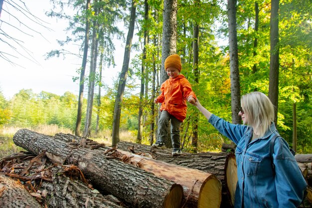 Moeder en zoon spelen op boomstammen in een bos