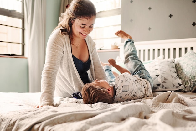 Moeder en zoon spelen op het bed.