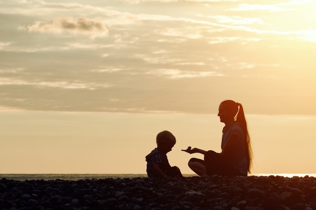 Moeder en zoon spelen op het strand met stenen