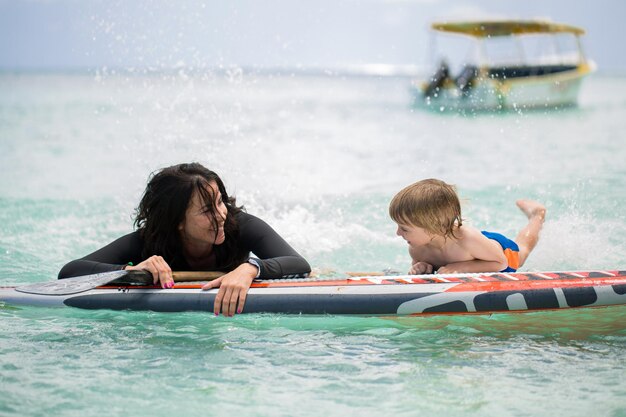 Moeder en zoon surfen in de oceaan op het bord