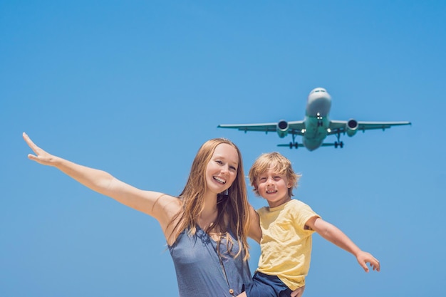 Moeder en zoon vermaken zich op het strand en kijken naar de landende vliegtuigen. Reizen op een vliegtuig met kinderen concept.