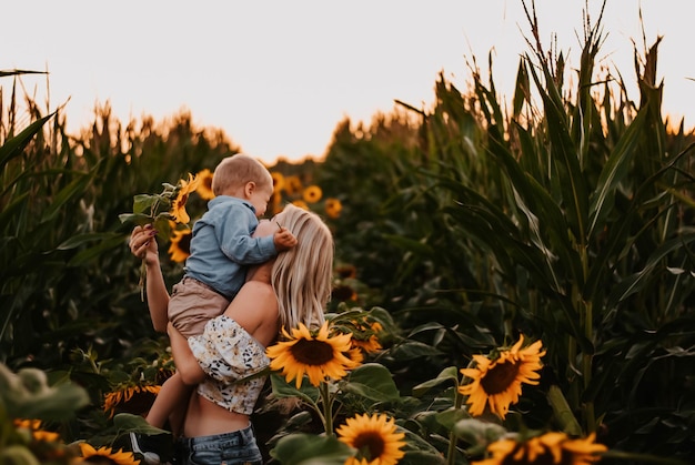 moeder en zoon zijn blij moeder en baby lachen zonnebloemveld de ondergaande zon