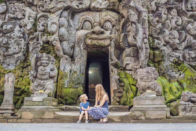 Moeder en zoon zijn toeristen in de oude hindoe-tempel van Goa Gajah in de buurt van Ubud op het eiland Bali, Indonesië. Reizen in Bali met kinderen concept