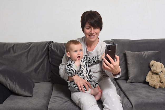 Moeder en zoon zittend op de bank, de moeder toont de smartphone aan de baby