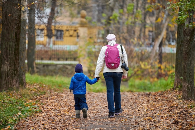 Moeder en zoontje lopen samen in herfst stadspark