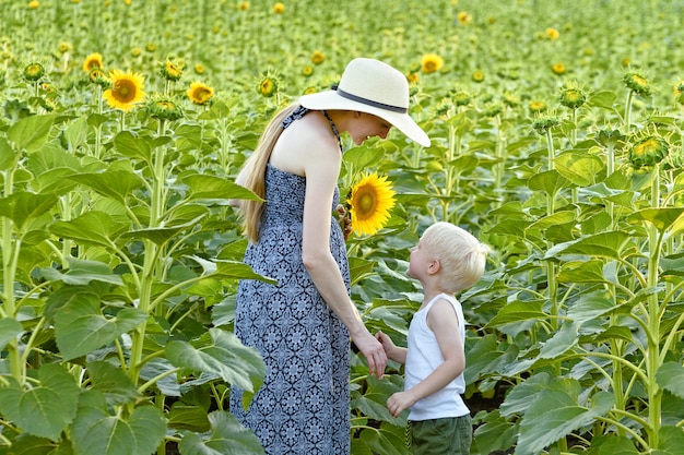 Moeder en zoontje staan tegen het bloeiende veld met zonnebloemen