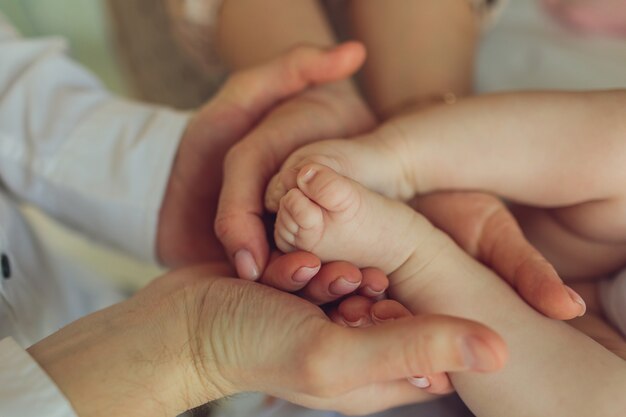 Foto moeder gebruikt haar hand om het kleine handje van haar baby vast te houden om hem haar liefde warm en veilig te laten voelen