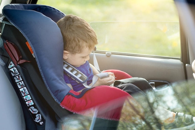 Moeder geeft de telefoon jongetje zit in een autostoeltje Veiligheid van het vervoer van kinderen