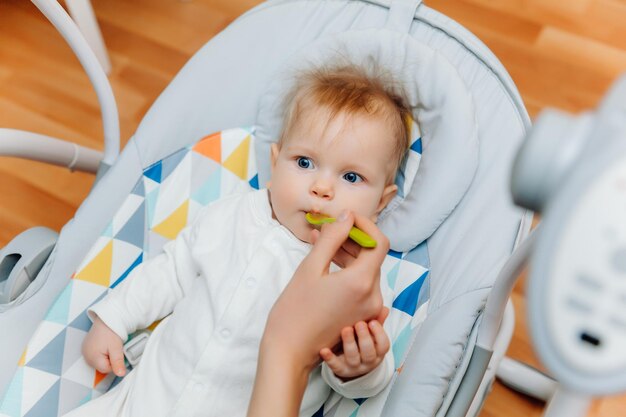 Moeder geeft fruitsaus aan baby moeder voedt baby op kinderstoel babyvoeding