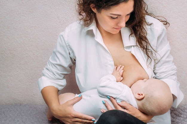 Moeder geeft haar baby borstvoeding op bed