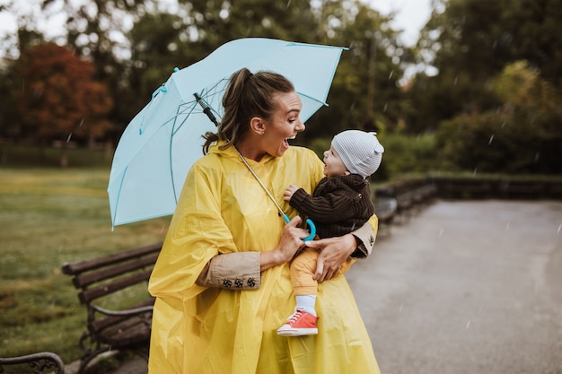 Moeder geniet van buiten in het park met haar baby terwijl het regent.