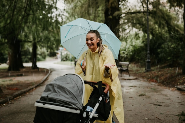 Moeder geniet van buiten in het park met haar baby terwijl het regent