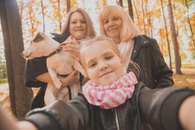 Foto moeder, grootmoeder en kleine kleindochter met jack russell terrier hond selfie nemen door smartphone buiten in de herfst natuur. familie, huisdieren en generatieconcept