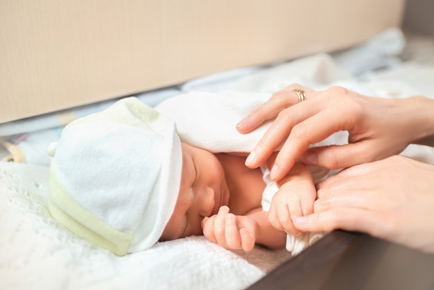 Foto moeder handen zorgen baby op witte kanten lakens.