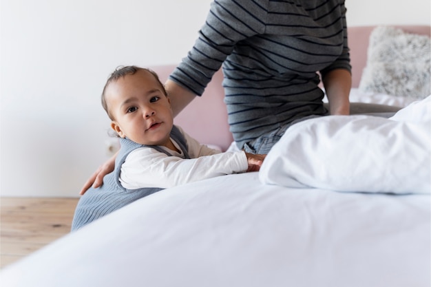 Foto moeder helpt haar baby op bed te kruipen