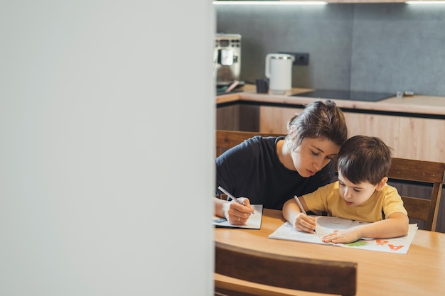 Moeder helpt haar zoon huiswerk schoolkind denkende ouder helpt kind