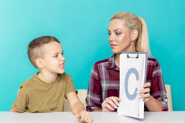 Moeder helpt haar zoon met huiswerk over geïsoleerde roze achtergrond. Verre onderwijs.