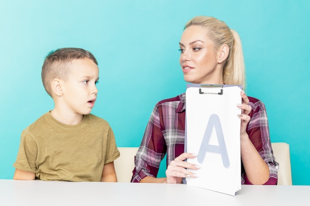 Moeder helpt haar zoon met huiswerk over geïsoleerde roze achtergrond. Verre onderwijs.