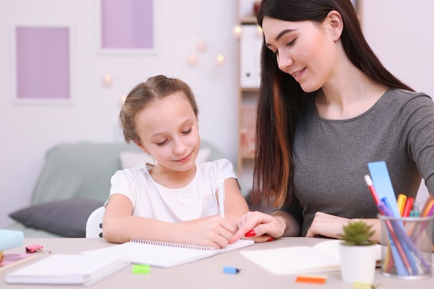 Moeder helpt het meisje om huiswerk te maken kinderen en ouders