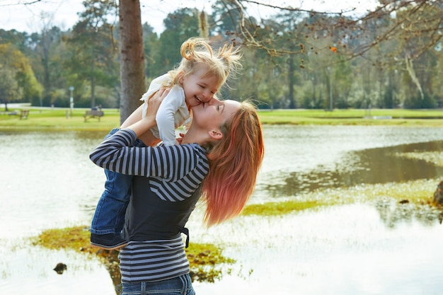Foto moeder het spelen die omhoog babymeisje in een meer werpen