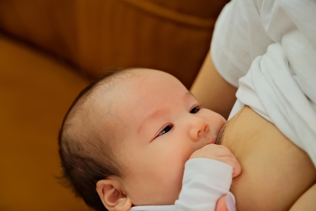 Moeder houdt de babybaby in haar armen en voedt een pasgeborene met moedermelk. Moeder geeft natuurlijke moedermelk