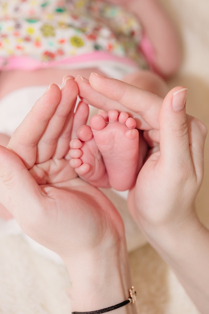 Moeder houdt de benen van de baby in zijn handpalmen