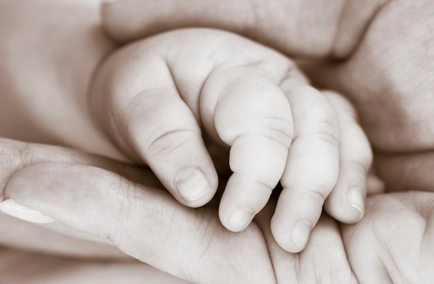 Moeder houdt de hand van een pasgeboren kind vast Liefdes- en zorgconcept Zwart-witfoto