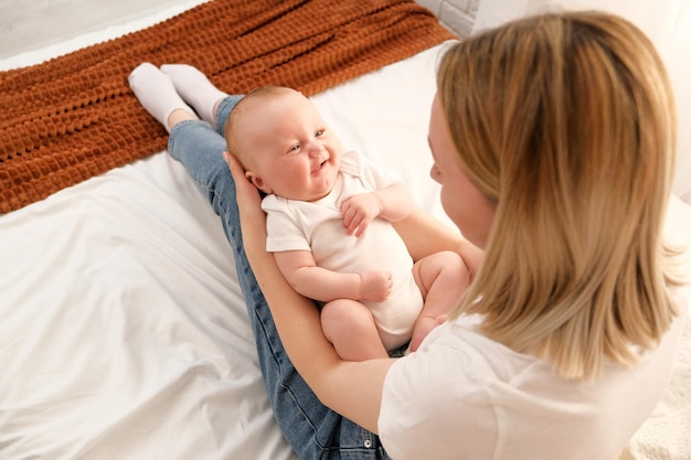 Moeder houdt een pasgeboren baby in haar armen op de achtergrond schijnt de zon uit het raam