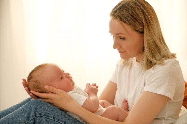 Moeder houdt een pasgeboren baby in haar armen op de achtergrond schijnt de zon uit het raam