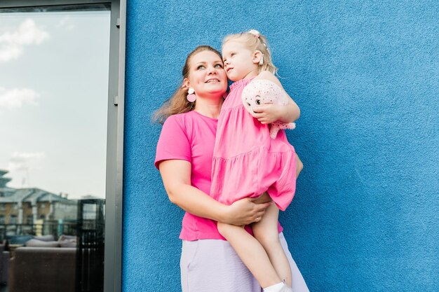 Foto moeder houdt en heeft plezier met haar kind met gehoorapparaten en cochleale implantaten zomer buiten doof en