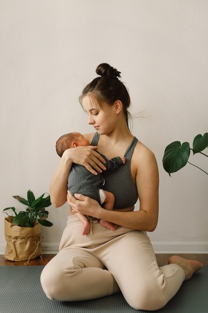 Moeder houdt haar pasgeboren zoontje vast en knuffelt thuis blije baby en moeder