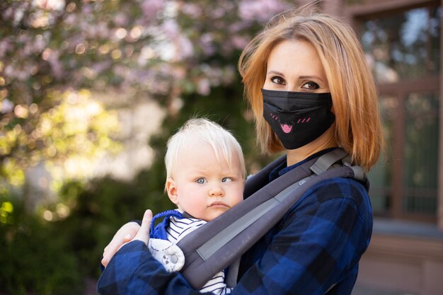 Moeder in masker met zoontje die in het park de sakuraboom speelt